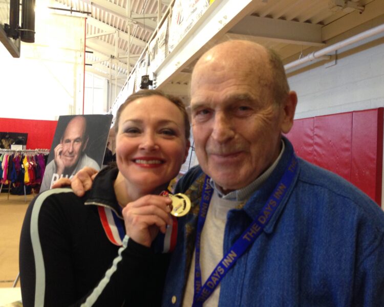 Allison holding a gold medal next to Dick Button, for the manleywoman skatecast, a figure skating podcast